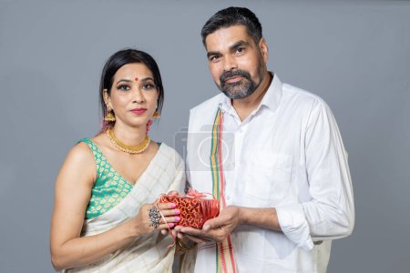 Téléchargez les photos : Portrait sur couple sud-indien tenant boîte cadeau regardant vers la caméra - en image libre de droit