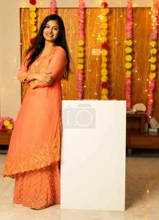 Photo for Full body portrait on indian woman with place card sign board with her and looking towards the camera - Royalty Free Image