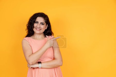 Photo for Portrait of excited young indian woman pointing finger smiling, having wow creative idea, yellow studio background, copyspace - Royalty Free Image