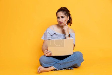 Photo for Indian girl sitting using laptop thoughtful expression isolated on color background - Royalty Free Image