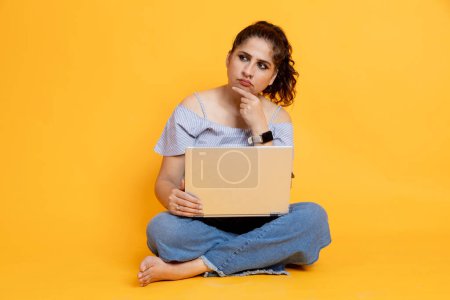 Photo for Indian girl sitting using laptop thoughtful expression isolated on color background - Royalty Free Image