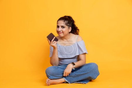 Photo for Young smiling happy woman in casual trendy clothing using mobile cell phone isolated on orange background studio. People lifestyle concept - Royalty Free Image
