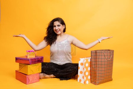 Photo for Indian girl sitting on floor with laptop doing online shopping from card, girl with laptop and gift box and shopping bag , online shopping concept - Royalty Free Image