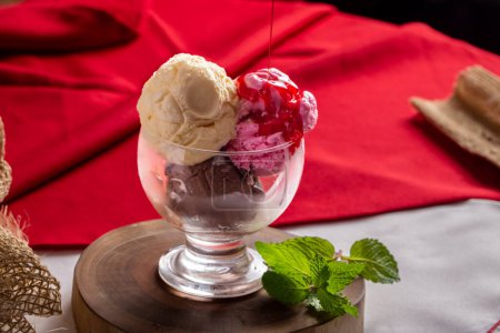 Photo for Strawberry syrup falling over Neapolitan ice cream. Glass bowl with ice cream in strawberry, vanilla and chocolate flavors. - Royalty Free Image