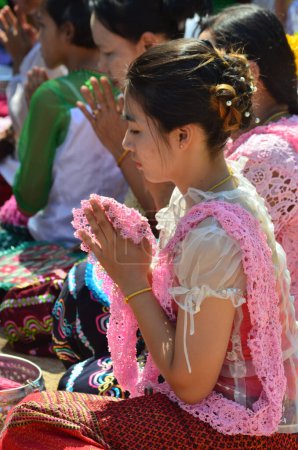 Foto de KANCHANABURI, TAILANDIA - 16 DE ABRIL DE 2016: Mujeres no identificadas de la minoría Mon se sientan y rinden homenaje a las pagodas de arena en Wat Wang Wiwekaram, distrito de Sunkhaburi, provincia de Kanchanaburi, en el festival Songkran. - Imagen libre de derechos
