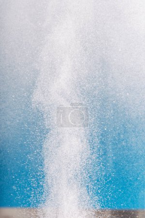 Säule aus Wasserstoffblasen im Wasser vor blauem Hintergrund.