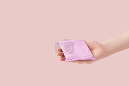 Téléchargez les photos : Sanitary pad in female hand against pink background. - en image libre de droit