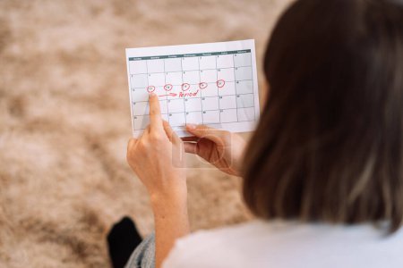 Téléchargez les photos : Lady looks at the days in the calendar menstrual cycle. - en image libre de droit