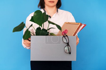 Foto de Girl in a white shirt holding a box of office supplies. - Imagen libre de derechos