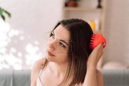 Photo for Woman enjoys doing herself a head massage with a scalp massager. - Royalty Free Image