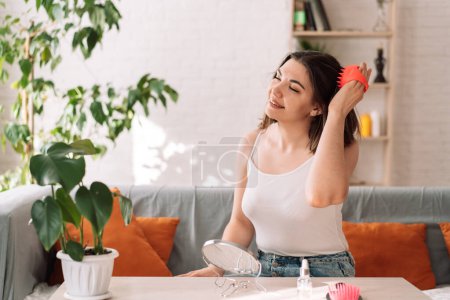 Photo for Lady enjoys giving herself a head massage with a scalp massager. - Royalty Free Image