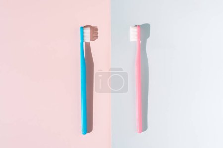 Téléchargez les photos : Brosse à dents bleue et rose sur fond rose et bleu sous une lumière dure. - en image libre de droit