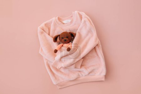 Photo for Soft pink jacket hugging a stuffed toy on a pink background. - Royalty Free Image