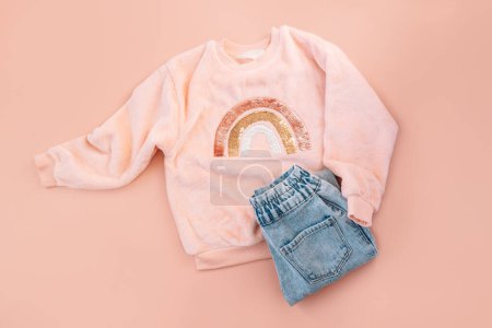Photo for Childrens pink sweater and blue jeans on a pink background. - Royalty Free Image