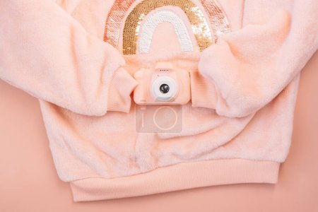 Photo for Childrens pink jacket holding a digital camera on a pink background. - Royalty Free Image