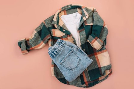 Photo for Childrens checkered shirt and blue jeans on a pink background. - Royalty Free Image