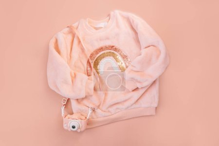 Photo for Childrens pink sweater and digital camera on a pink background. - Royalty Free Image