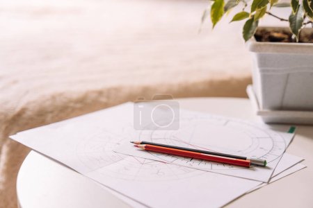 Carte natale sur papier blanc avec crayons sur une table avec une fleur en face du lit.