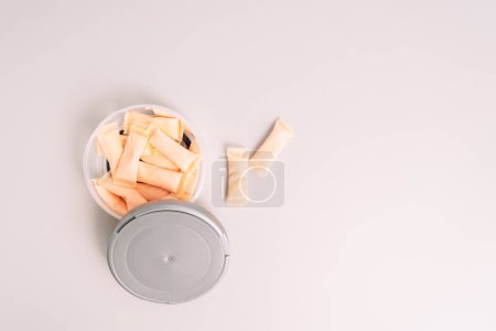 Plastic jar with fruit flavored snus sachets on a light background.