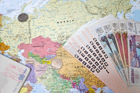 Téléchargez les photos : Moscow, Russia - February 19 2019: Composition made of a world map centered in Central Asia with on it, some Russian banknotes and coins as well as some train tickets and an open French passport with an entry stamp. All the objects are arranged aroun - en image libre de droit