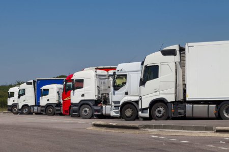 Téléchargez les photos : Row of cab over semi-trailer trucks parked in a highway parking lot. - en image libre de droit