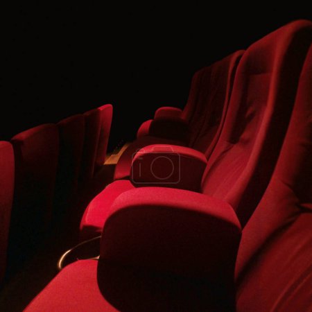 Téléchargez les photos : Des rangées de sièges en velours rouge dans un endroit sombre et totalement vide. - en image libre de droit