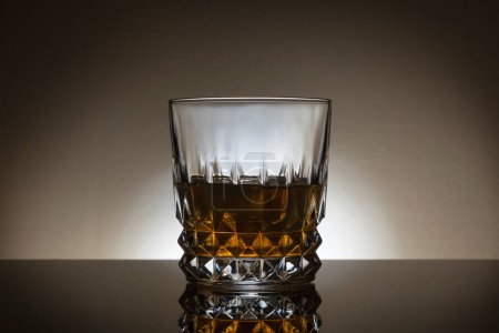 Photo for Backlit Whiskey glass on a dark background with reflection in front of the glass. - Royalty Free Image