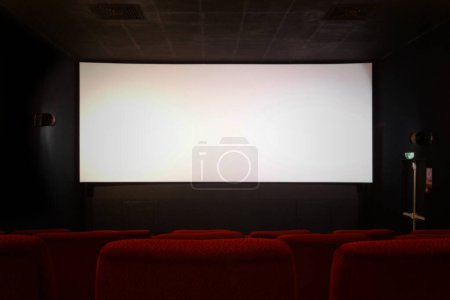 Téléchargez les photos : Rangée de sièges rouges dans un cinéma avec les blancs quelques minutes avant le début du film. L'écran blanc peut éventuellement être champ avec n'importe quoi - en image libre de droit