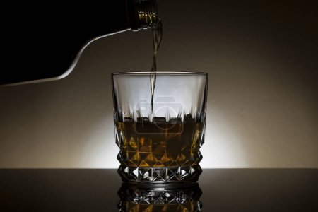 Photo for Whiskey being poured into a backlit glass. - Royalty Free Image