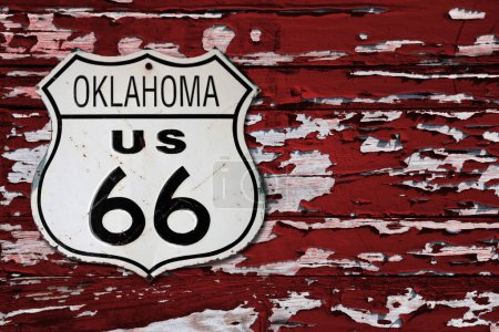 Téléchargez les photos : Gros plan sur un panneau de route Oklahoma US 66 vissé sur un mur en bois peint en rouge. - en image libre de droit