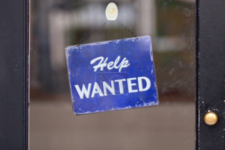Closed-up on a blue sign with written in it: Help wanted.