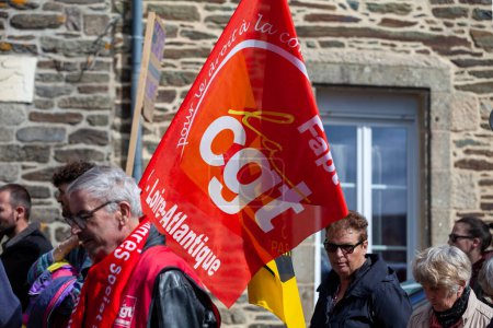 Photo for Carhaix, France - May 1 2023: Demonstration against the pension reform with a demonstrator waving a CGT flag, a national trade union center. - Royalty Free Image