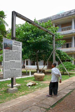 Photo for Phnom Penh, Cambodia - July, 16 2006: Old Cambodian man reading a placard about the "gallows" in S21, the former prison during the Khmer Rouge regime. - Royalty Free Image
