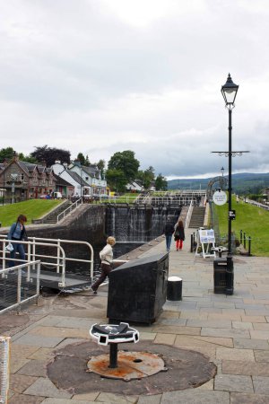 Photo for Fort Augustus, Scotland - July 01 2007: Caledonian Canal in Fort Augustus with some tourists heading for the departure of the cruise on the Loch Ness. - Royalty Free Image