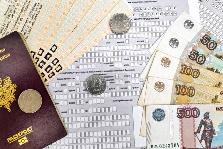 Photo for Some rubles coins and banknotes with a French passport and train tickets on top of a special foreign citizen arrival notification form. - Royalty Free Image