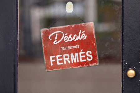 Rotes offenes Schild mit französischer Aufschrift: "Desole, nous sommes fermes", was auf Englisch "Sorry, we 're closed" bedeutet.".