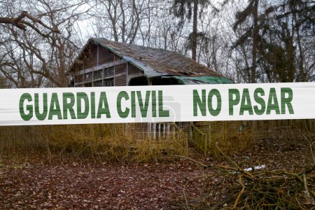 Verlassene Hütte im Wald mit einem Polizeiband mit der Aufschrift "Guardia Civil, no pasar".