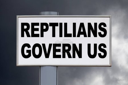 Close-up on a white billboard against a cloudy sky with the message "Reptilians govern us" written in the middle.