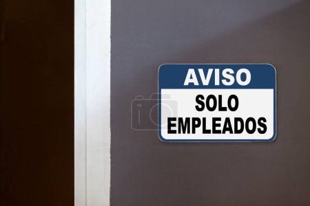 Blue and white notice sign on the side of an open door stating in Spanish : "Aviso, Solo empleados", meaning "Notice, Employees only".