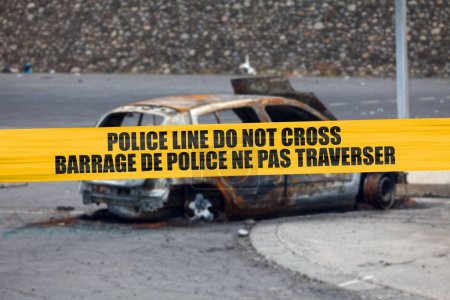 Car burnt by a pyromaniac with a police tape with written in it in English "Police line do not cross" and French "Barrage de police ne pas traverser".