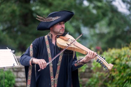 Téléchargez les photos : Locronan, France - 07 mai 2023 : Troubadour en tenue médiévale jouant au rebec. - en image libre de droit
