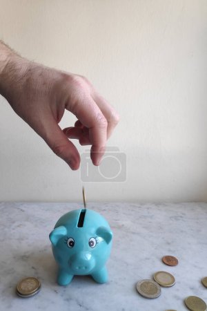 A man feeding the piggy bank with euro coins.