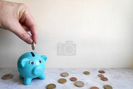 A man feeding the piggy bank with euro coins.