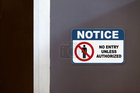 Panneau bleu et blanc sur le côté d'une porte ouverte indiquant "Avis, Aucune entrée sauf autorisation".
