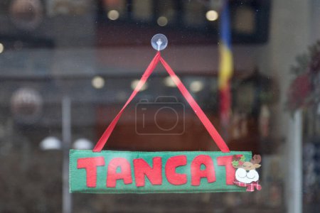 Old fashioned sign in the window of a shop saying in Catalan "Tancat", meaning in English "Closed".