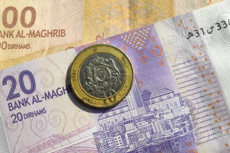 Close-up on a 10 Moroccan dirham coin on top of a banknote of 20 and 100.
