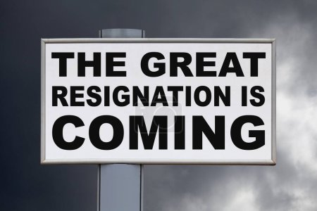 Close-up on a white billboard against a blue sky with the message "The great resignation is coming" written in black in the middle.