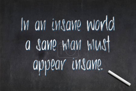 Blackboard with a quote from the 19th century British writer Charles William King saying "In an insane world a sane man must appear insane.", drawn in the middle.