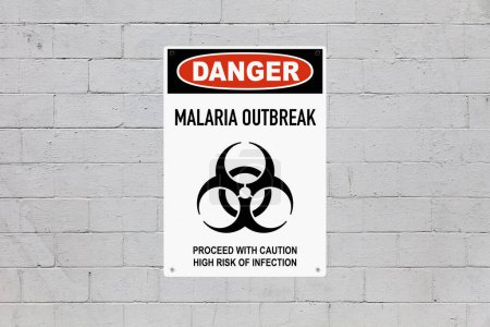 Black, red and white danger sign attached on a brick wall painted in grey. The sign stating : Danger - Malaria outbreak - Proceed with caution, high risk of infection.