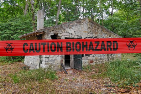 Téléchargez les photos : Maison en pierre abandonnée dans les bois avec une bande de police avec écrit dedans "Mise en garde Biohazard". - en image libre de droit